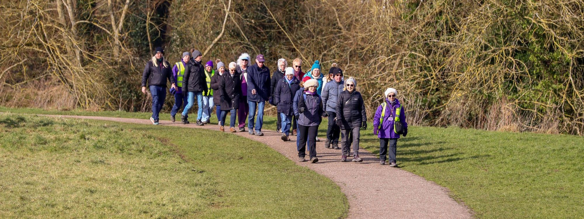 People walking together along a green path in Milton Keynes on a sunny morning